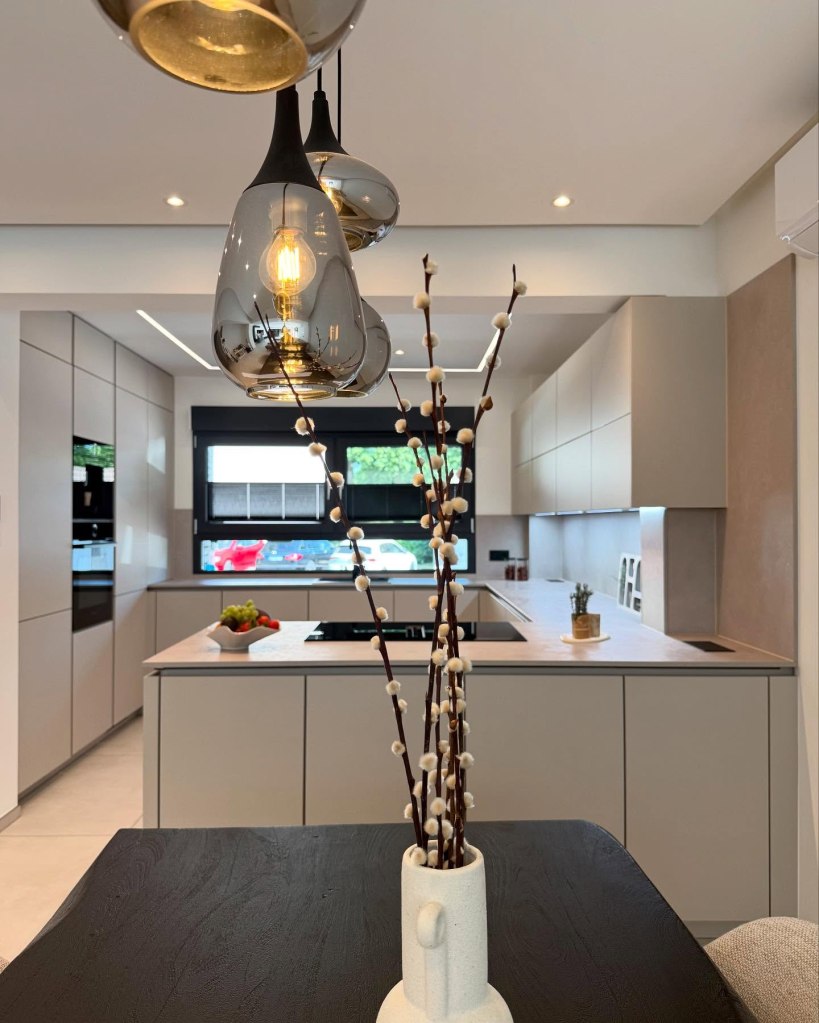 Moderne Küche mit eleganten Hängeleuchten und einem Tisch mit Vase und Dekoration.